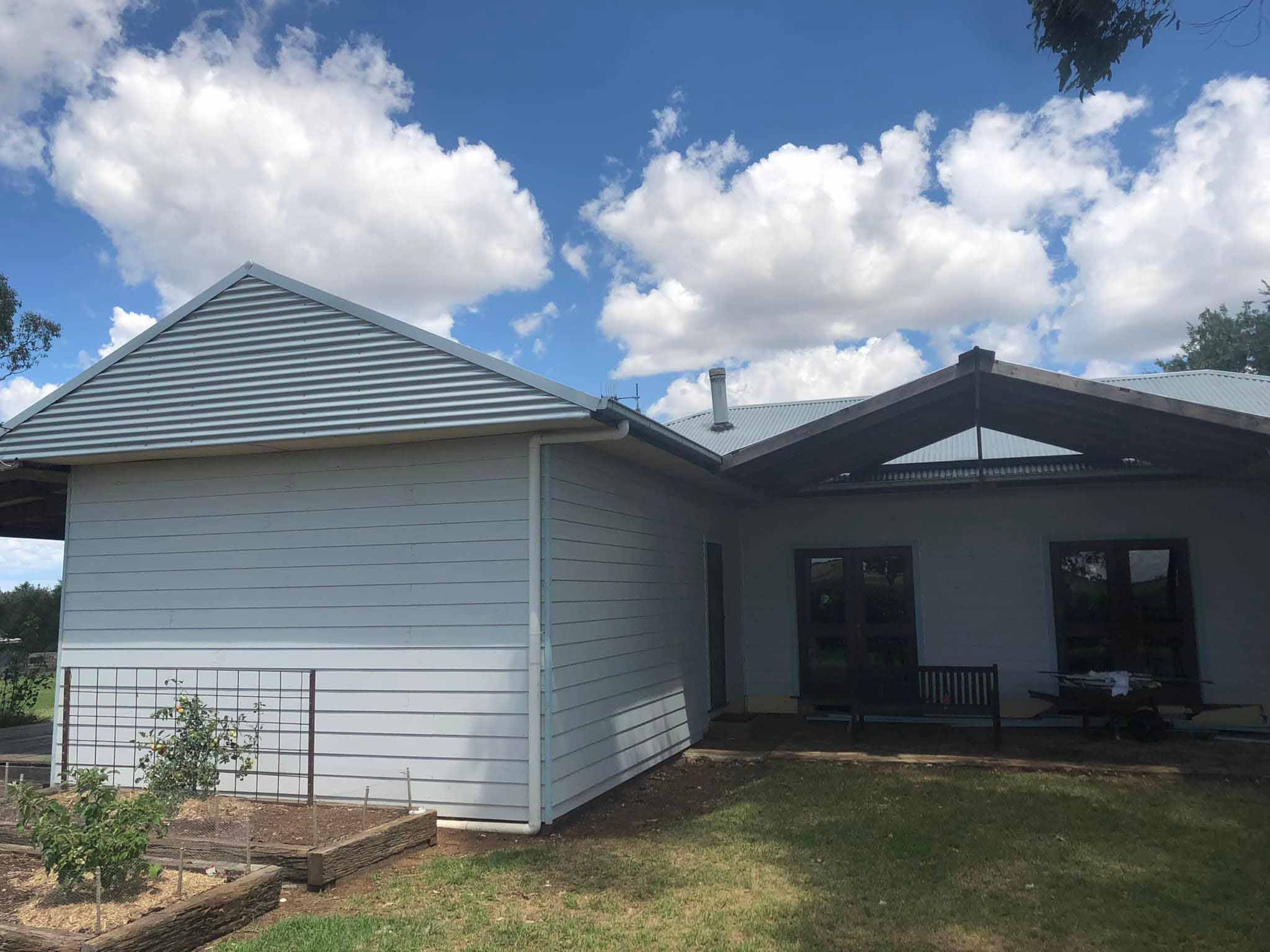 Weatherboard house extension with a gabled roof behind a lawn